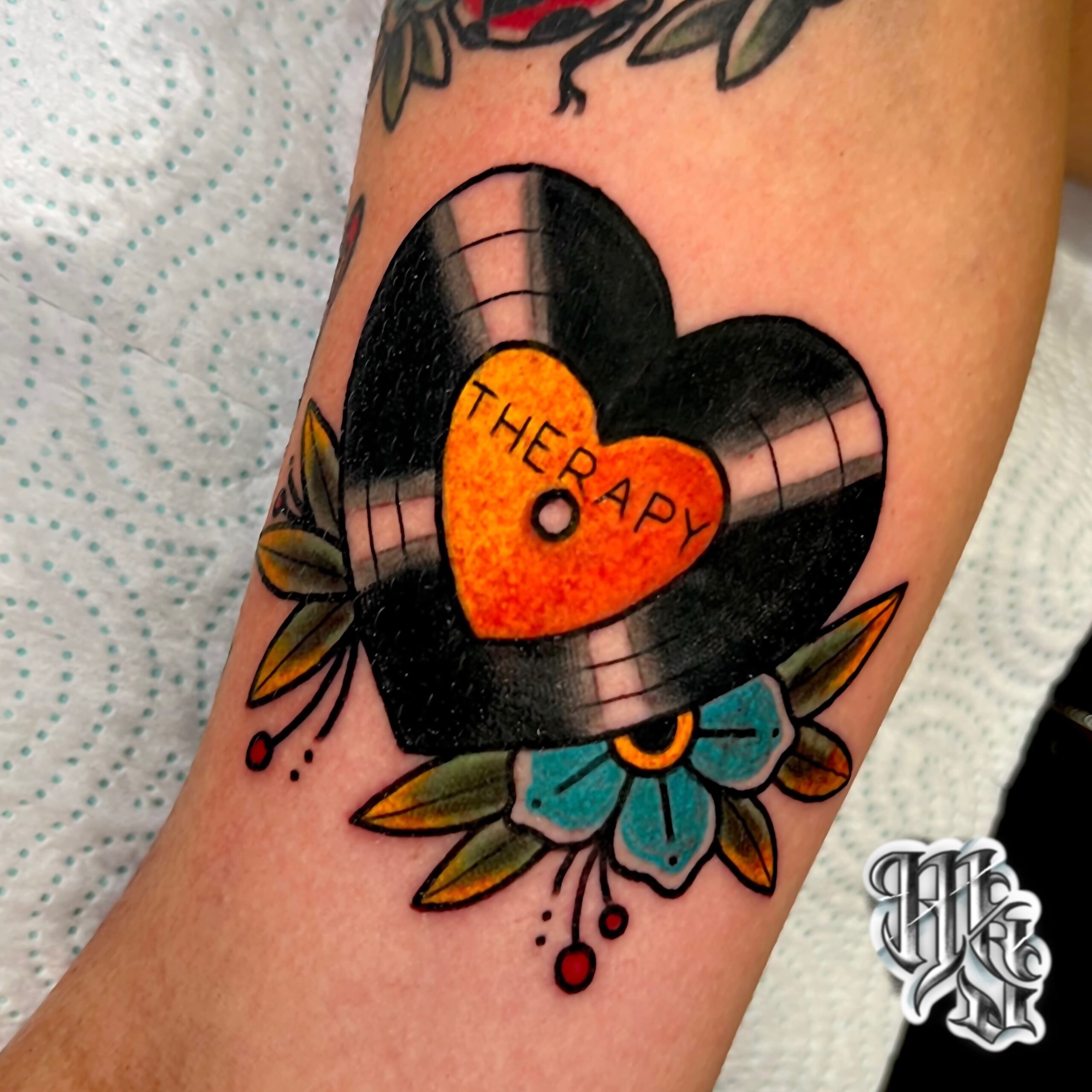 Amantes de la musica, tatuaje de disco de vinilo en forma de corazon en estilo tradicional , realizado en estudio profesional de madrid